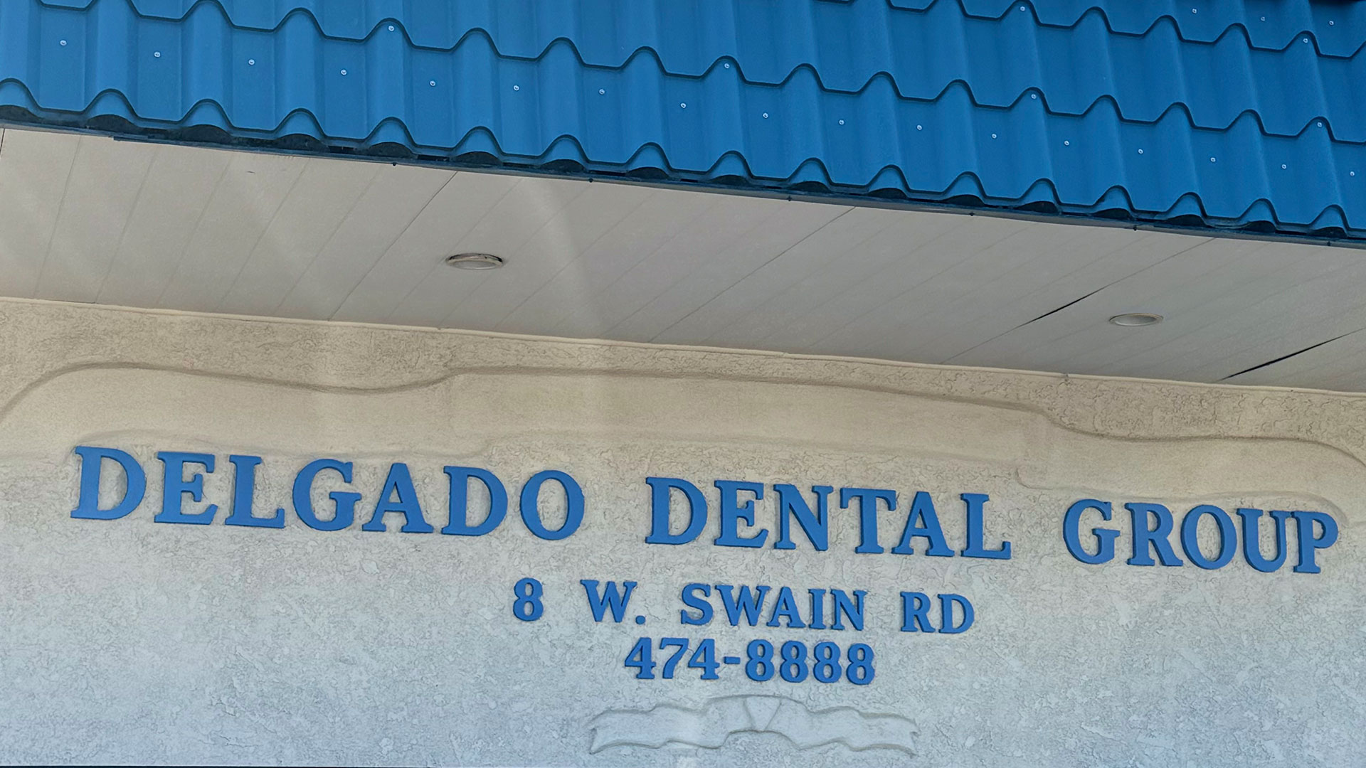 The image shows a sign for  DELGADO DENTAL GROUP  with contact information provided.