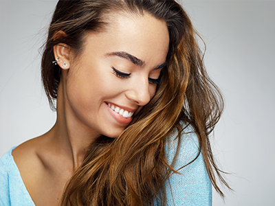 The image is a close-up portrait of a woman with long hair, smiling at the camera.